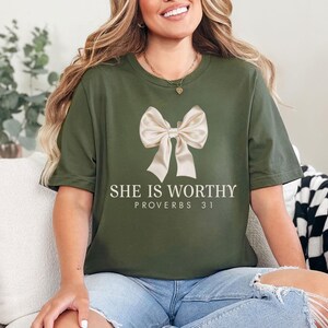 May include: A green t-shirt with a white bow and the text "She is Worthy Proverbs 31" printed on the front.