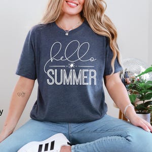 May include: A navy blue t-shirt with the text "hello summer" in white lettering. The shirt features a simple sun graphic.