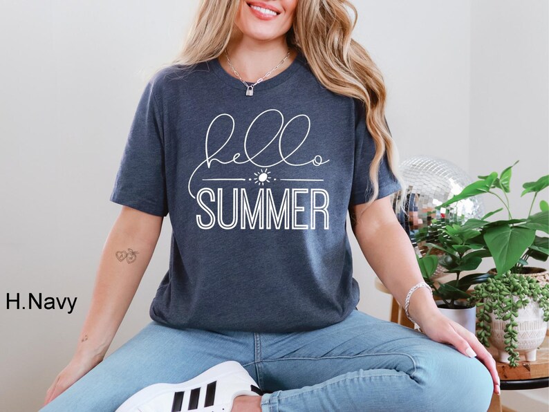 May include: A navy blue t-shirt with the text "hello summer" in white lettering. The shirt features a simple sun graphic.