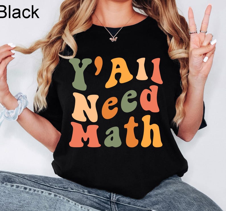 K&ouml;nnte beinhalten: Schwarzes T-Shirt mit dem Text "Y'All Need Math" in bunten, Retro-Lettern.