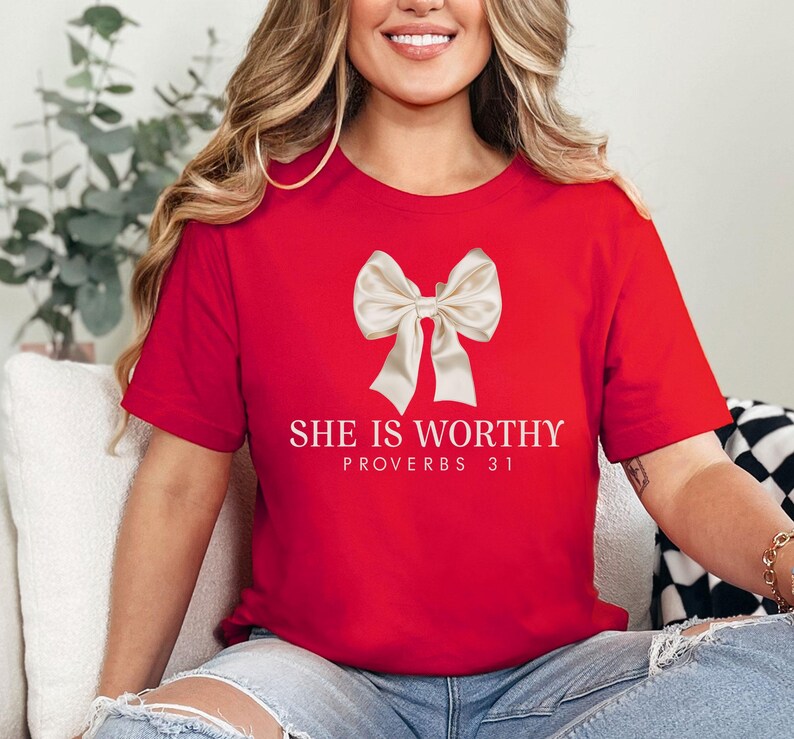 May include: Red t-shirt with a white bow and the text "SHE IS WORTHY PROVERBS 31" printed on the front.