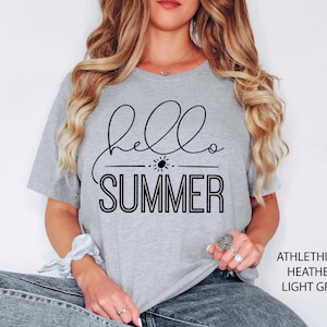 May include: A light grey t-shirt with the text "hello summer" in black lettering. The text is in a cursive font with a sun graphic above the word "summer".