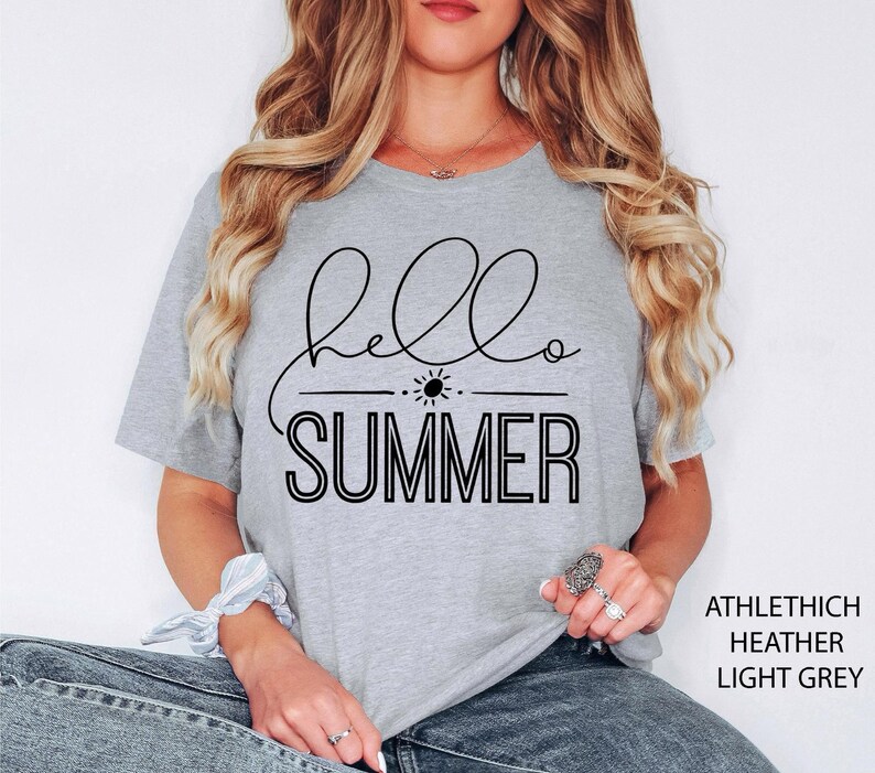 May include: A light grey t-shirt with the text "hello summer" in black lettering. The text is in a cursive font with a sun graphic above the word "summer".