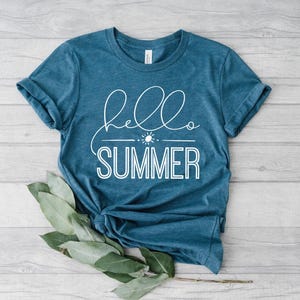 May include: A teal blue t-shirt with the text "hello summer" in white lettering. The text is in a cursive font with a sun and a line underneath.
