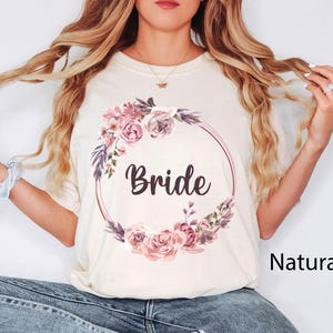 Pode incluir: Uma camiseta branca com um design de coroa de flores e a palavra "Bride" no centro. A camiseta &eacute; de cor natural.