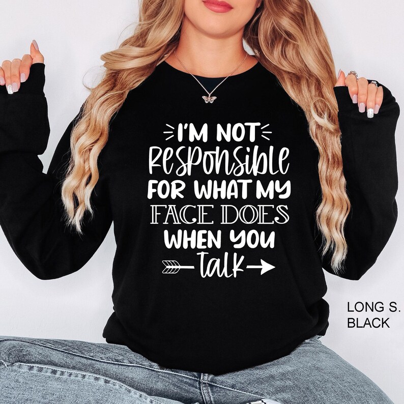 K&ouml;nnte beinhalten: Schwarzes Langarmshirt mit wei&szlig;em Text, der "Ich bin nicht verantwortlich f&uuml;r das, was mein Gesicht tut, wenn du sprichst" lautet, mit Pfeilen, die nach links und rechts zeigen.