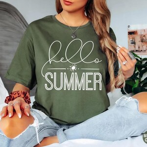 May include: A green t-shirt with the text "hello summer" in white lettering. The shirt has a simple design with a sun graphic above the text.