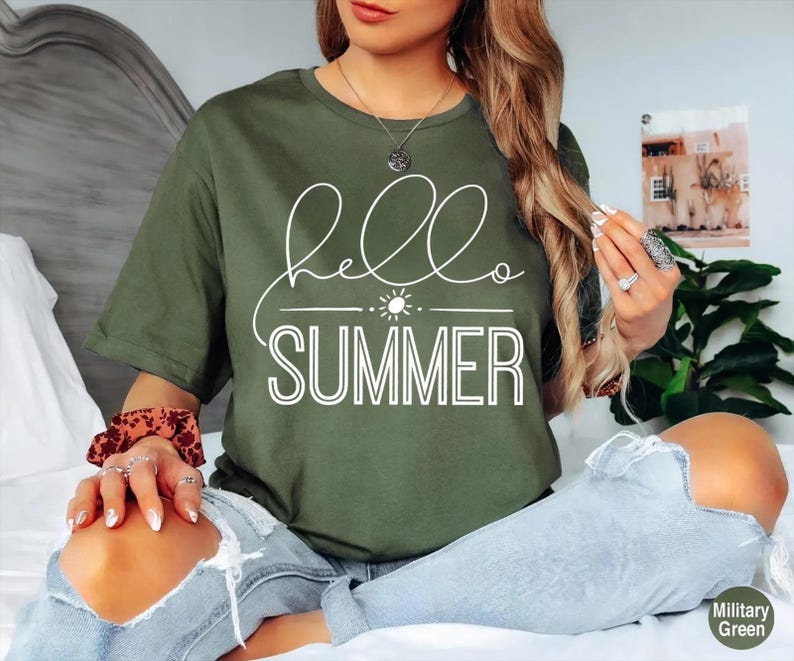 May include: A green t-shirt with the text "hello summer" in white lettering. The shirt has a simple design with a sun graphic above the text.