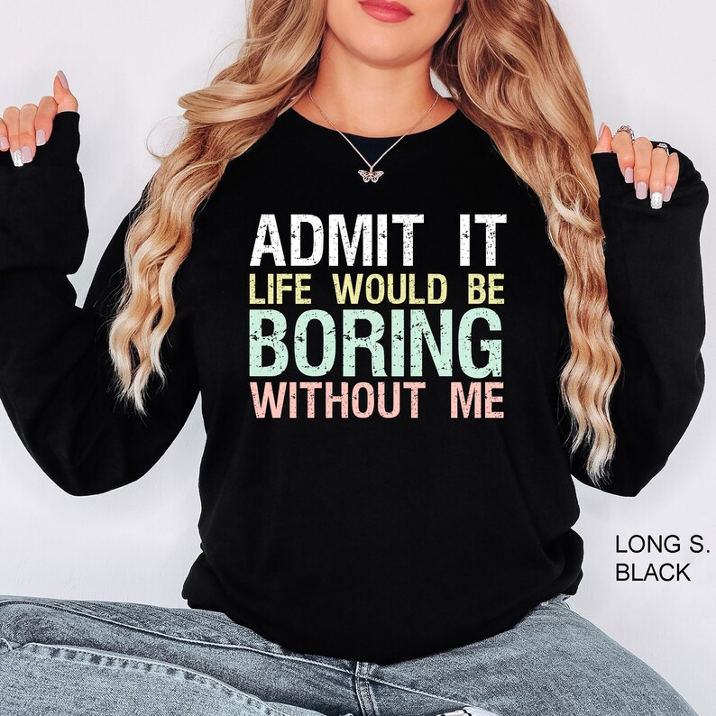 May include: Black long-sleeve sweatshirt with the text "ADMIT IT LIFE WOULD BE BORING WITHOUT ME" in white, yellow, green, and pink. The sweatshirt is a casual style.