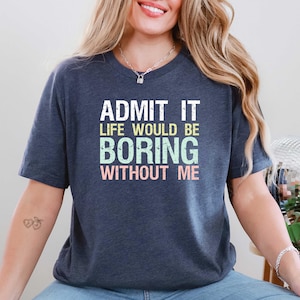 May include: Navy blue t-shirt with the text "ADMIT IT LIFE WOULD BE BORING WITHOUT ME" in white, green, and pink. The shirt has short sleeves and a crew neck.