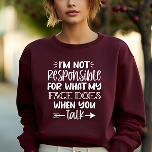 K&ouml;nnte beinhalten: Burgunderfarbener Pullover mit wei&szlig;em Text, der "Ich bin nicht verantwortlich f&uuml;r das, was mein Gesicht tut, wenn du sprichst" lautet, mit einem wei&szlig;en Pfeil, der nach rechts und links zeigt.