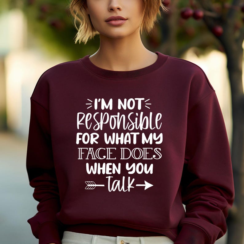 K&ouml;nnte beinhalten: Burgunderfarbener Pullover mit wei&szlig;em Text, der "Ich bin nicht verantwortlich f&uuml;r das, was mein Gesicht tut, wenn du sprichst" lautet, mit einem wei&szlig;en Pfeil, der nach rechts und links zeigt.