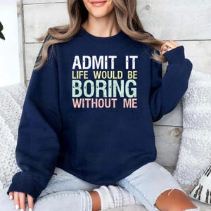 May include: Navy blue sweatshirt with the text "ADMIT IT LIFE WOULD BE BORING WITHOUT ME" in white, green, and pink lettering. The sweatshirt is a casual style, suitable for everyday wear.