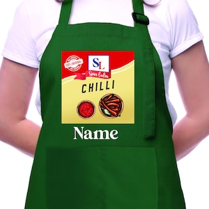 May include: Green apron with a red, yellow, and white label that says "Spice Ladies Chilli" and has a picture of chili peppers and chili paste. The apron has a pocket and a name tag that says "Name".