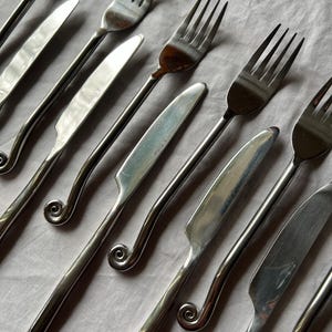 May include: A set of three ceramic mugs with a speckled, matte finish in cream, light grey, and dark grey. Each mug has a simple, minimalist design and a rounded handle.