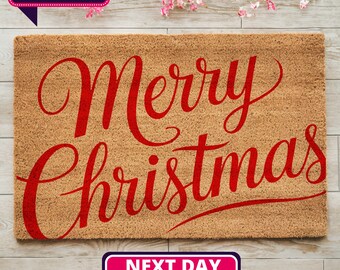 May include: A brown coir doormat with the words "Merry Christmas" in red cursive lettering.