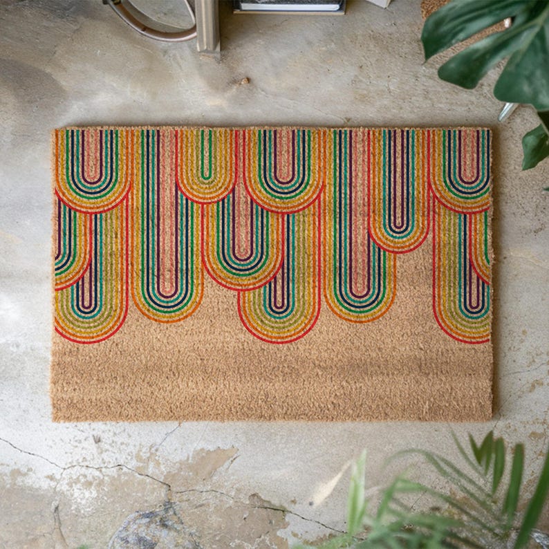 May include: A coir doormat with a colorful rainbow design. The rainbow is made up of multiple arches in shades of red, orange, yellow, green, blue, and purple.