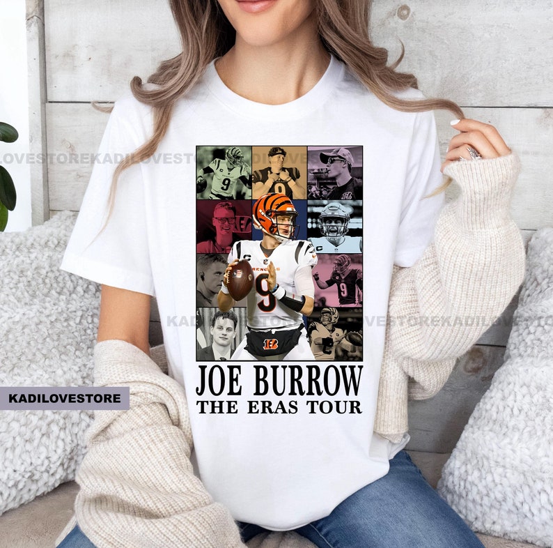 Pu&ograve; includere: Maglietta bianca con un collage di immagini di Joe Burrow, un giocatore di football americano, in diverse uniformi. Il testo "Joe Burrow The Eras Tour" &egrave; stampato sotto il collage.