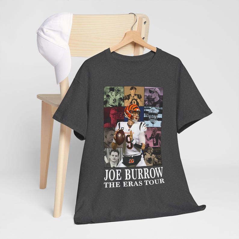 Pu&ograve; includere: Una maglietta grigio scuro con un collage di immagini di Joe Burrow, un giocatore di football americano, in diverse pose. Il testo "Joe Burrow The Eras Tour" &egrave; stampato sul fondo della maglietta.