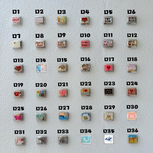 May include: A collection of silver-toned charm beads with various designs and text. The charms feature phrases like "Mom," "Dad," "My Son," and "I Love My Cat." Other charms have images of hearts, butterflies, and other symbols.