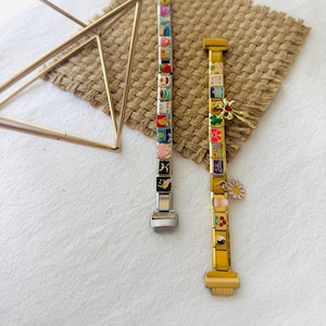 May include: Two charm bracelets with colorful enamel charms. The bracelet on the left is silver with a silver clasp. The bracelet on the right is gold with a gold clasp. Both bracelets have a variety of charms, including hearts, stars, flowers, and animals.