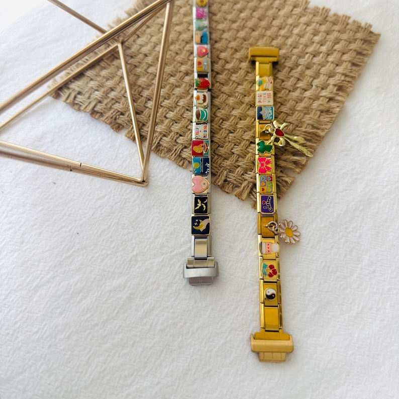 May include: Two charm bracelets with colorful enamel charms. The bracelet on the left is silver with a silver clasp. The bracelet on the right is gold with a gold clasp. Both bracelets have a variety of charms, including hearts, stars, flowers, and animals.