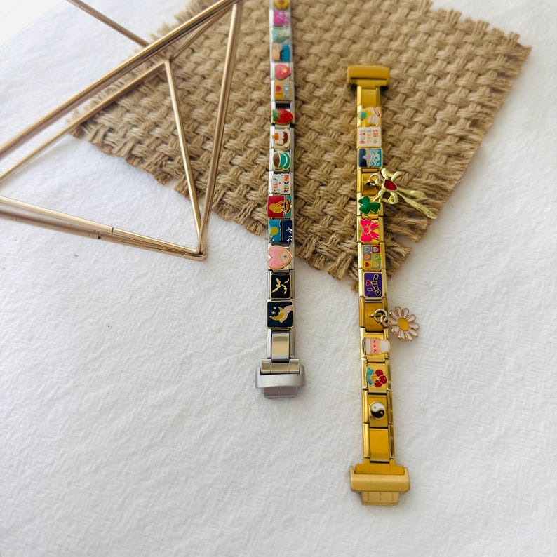 May include: Two charm bracelets with colorful enamel charms. The bracelet on the left is silver with a silver clasp. The bracelet on the right is gold with a gold clasp. Both bracelets have a variety of charms, including hearts, stars, flowers, and animals.
