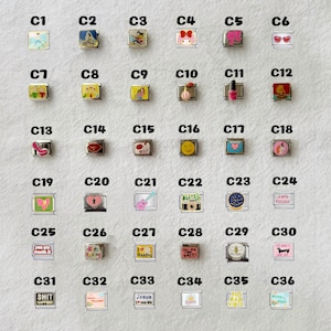 May include: A collection of thirty-six rectangular modular charm links arranged in a grid, each featuring unique colorful enamel designs, icons, and text labels ranging from C1 to C36, designed for attachment to a modular link bracelet.
