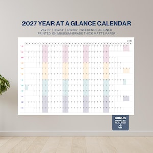 Peut inclure: Un grand calendrier annuel 2027, disponible en 61x46cm, 91x61cm et 122x91cm. Le calendrier est imprimé sur du papier mat épais avec les week-ends alignés. Comprend un ensemble imprimable bonus. Le calendrier est affiché sur un mur blanc.