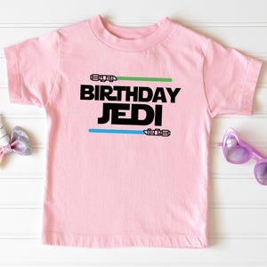 a pink t - shirt and sunglasses on a white background