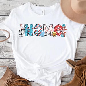 May include: White t-shirt with a colorful graphic of the word "NAME" featuring characters from the book "The Cat in the Hat".