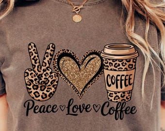 May include: Espresso-colored t-shirt featuring a peace sign, heart, and coffee cup graphic. The peace sign and coffee cup have a leopard print design. The heart is gold glitter. The words "Peace Love Coffee" are printed below.