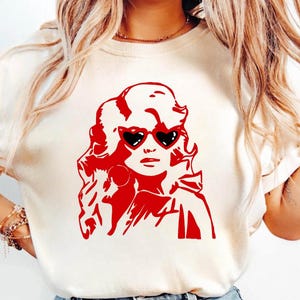 May include: A white t-shirt with a red silhouette of a woman wearing heart-shaped sunglasses.