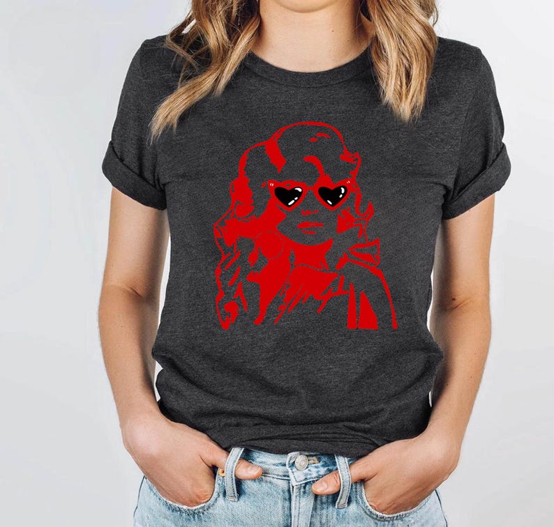 May include: A dark gray t-shirt with a red silhouette of a woman wearing heart-shaped sunglasses. The woman's hair is styled in a large, curly updo.