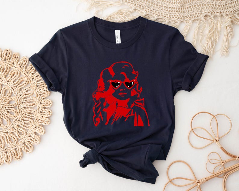 May include: A navy blue t-shirt with a red graphic of a woman wearing heart-shaped sunglasses.