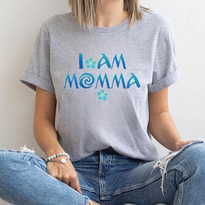 Pode incluir: Uma camiseta cinza com o texto "I am Momma" em azul e amarelo. O texto &eacute; estilizado com um redemoinho azul e uma flor amarela.