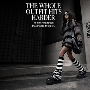 May include: A distressed black and grey striped long-sleeve sweater, black shoulder bag, and black and white striped leg warmers worn with black platform shoes. Text reads: THE WHOLE OUTFIT HITS HARDER. The finishing touch that makes the look.
