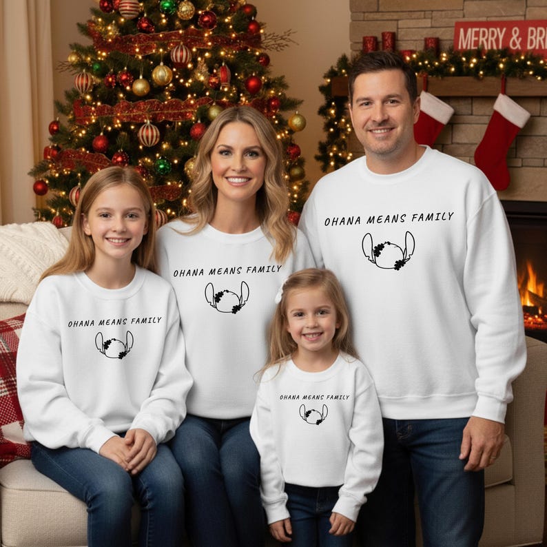 May include: A family of four wearing matching white sweatshirts with the text "OHANA MEANS FAMILY" and a black graphic. The family is posing in front of a decorated Christmas tree and a fireplace.