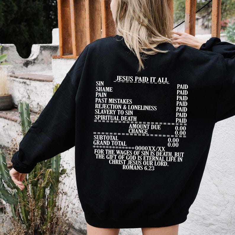 May include: Black sweatshirt with white text that reads "JESUS PAID IT ALL" and a receipt-style list of sins and the price paid for them. The text at the bottom reads "FOR THE WAGES OF SIN IS DEATH, BUT THE GIFT OF GOD IS ETERNAL LIFE IN CHRIST JESUS OUR LORD. ROMANS 6.23"