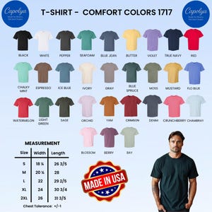 Op de afbeelding: Een selectie Comfort Colors 1717 T-shirts in diverse kleuren, waaronder zwart, wit en rood. De afbeelding toont een maattabel met afmetingen in inches en een "Made in USA"-embleem. Een man poseert in een donkergroen t-shirt.