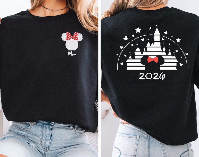 Puede incluir: Sudadera negra con un dise&ntilde;o de Minnie Mouse blanco y un lazo rojo, con la palabra "Mam&aacute;". La parte trasera presenta un dise&ntilde;o de castillo blanco, un lazo de Minnie Mouse y el a&ntilde;o "2026".