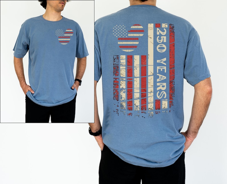May include: A blue short-sleeved t-shirt with a distressed American flag design on the front and back. The front features a Mickey Mouse-inspired flag, while the back displays a vertical flag design with the text "250 YEARS".