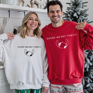 May include: A couple wearing matching sweatshirts, one white and one red. Both sweatshirts feature the text "OHANA MEANS FAMILY" and a Stitch graphic. The sweatshirts are part of a family matching set, perfect for Christmas or family gatherings.
