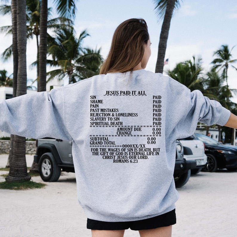May include: Gray sweatshirt with a receipt-style graphic that reads "Jesus Paid It All". The graphic lists various sins and states that they have been paid for. The text at the bottom reads "For the wages of sin is death, but the gift of God is eternal life in Christ Jesus our Lord. Romans 6:23."