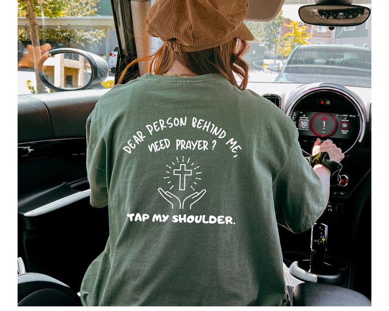 May include: A green t-shirt with the text "Dear person behind me, need prayer? Tap my shoulder." and a white cross graphic.