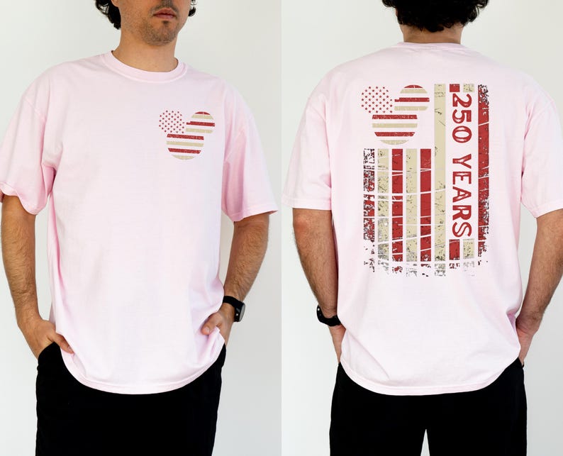 May include: A pale pink t-shirt with a Mickey Mouse-themed design in red and white stripes and dots. The back of the shirt has a larger design with the text "250 YEARS" in red. The shirt is worn by a person.