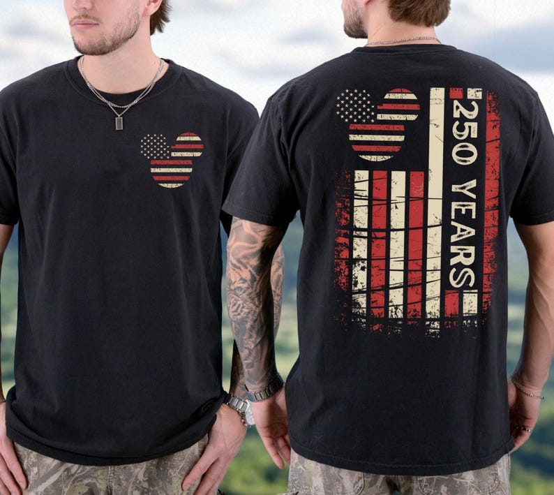 May include: Black t-shirt with a patriotic design. The front features a Mickey Mouse head in a US flag pattern. The back displays a larger flag design with the text "250 YEARS". A casual, comfortable garment.