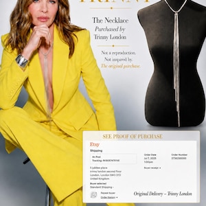 May include: A silver-toned necklace featuring a delicate chain that splits into multiple long, thin, dangling strands. The necklace is displayed on a black mannequin bust, showcasing a minimalist design with a polished metallic finish and a secure clasp.