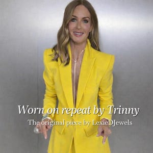 Könnte beinhalten: Ein leuchtend gelber Anzug, bestehend aus Blazer und Hose. Der Blazer hat einen taillierten Schnitt mit strukturierten Schultern. Der Text auf dem Bild lautet "Worn on repeat by Trinny" und "The original piece by LexieDJewels".