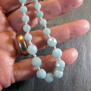 May include: A light blue gemstone necklace with faceted beads and a white cord.
